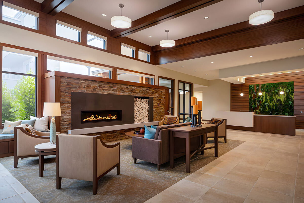warm and inviting senior living common area featuring lounge seating, fireplace, and wood accents for a comfortable atmosphere