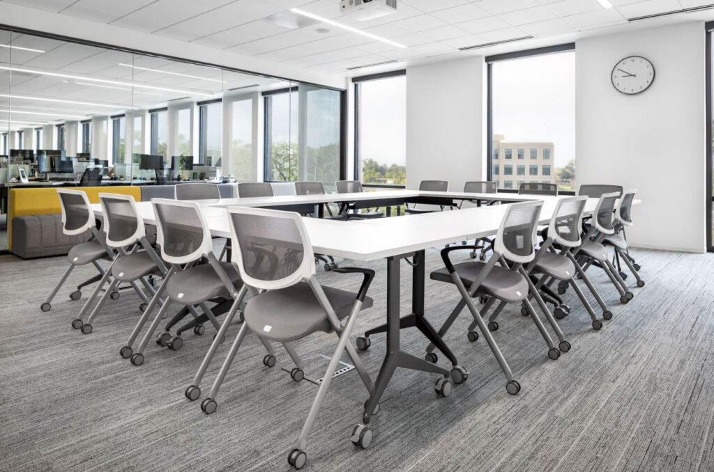 Employee training room with mobile tables, white task chairs, monitors, and abundant natural light