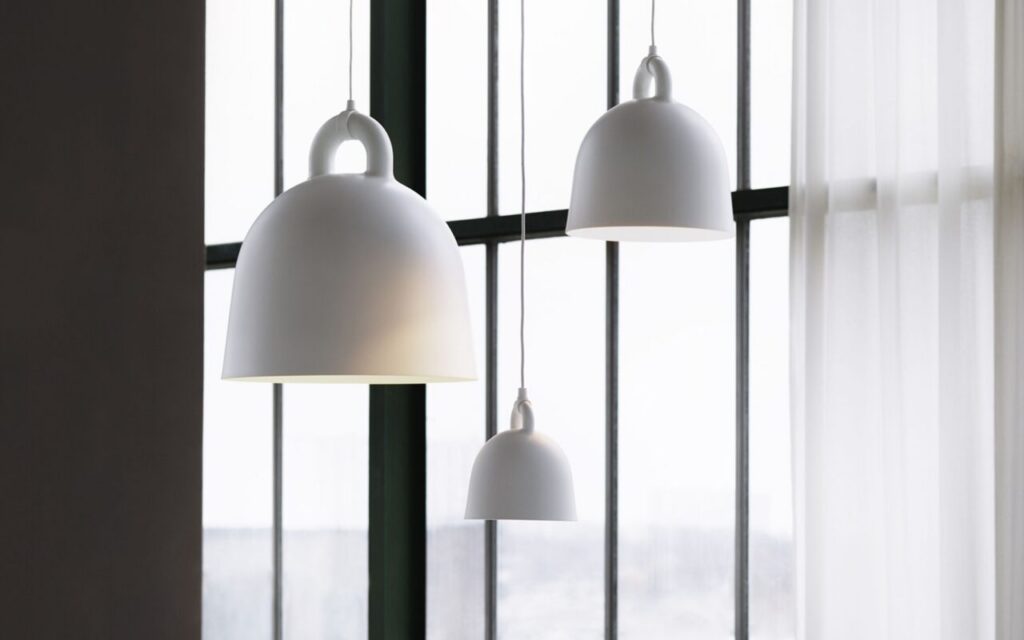 Gray Bell pendant lights hanging at varied heights in front of large commercial windows