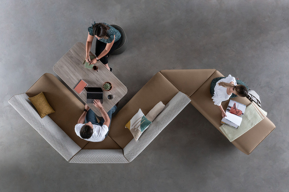 Overhead view of employees using a curved collaborative seating area with integrated work surfaces