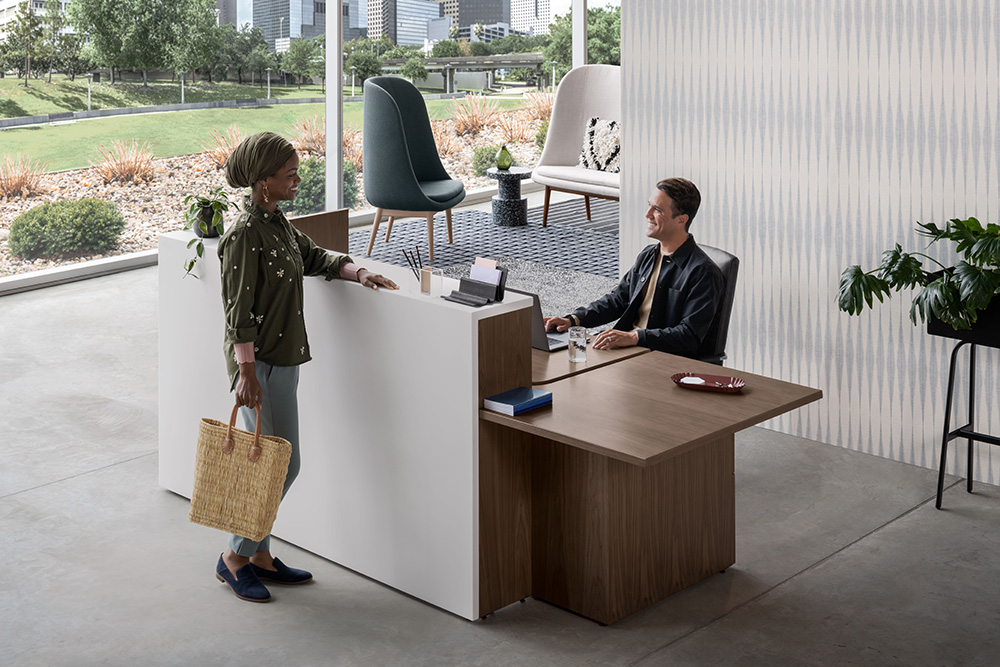 Silea welcome station with a reception desk, guest seating, storage, and two employees meeting
