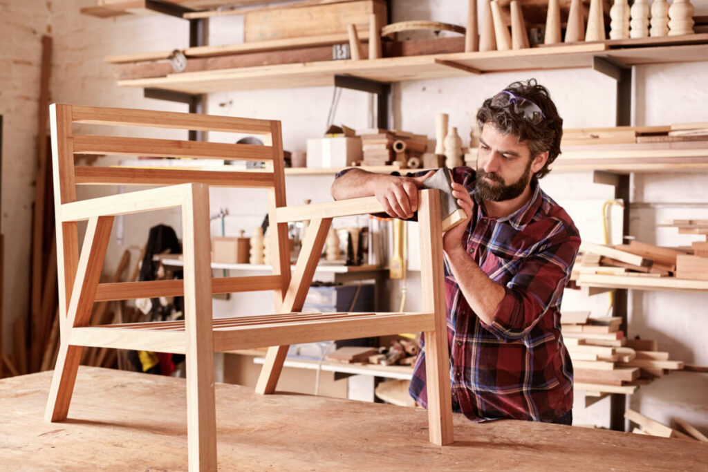 Modern Business Interiors technician refinishing wood office furniture in a professional workshop