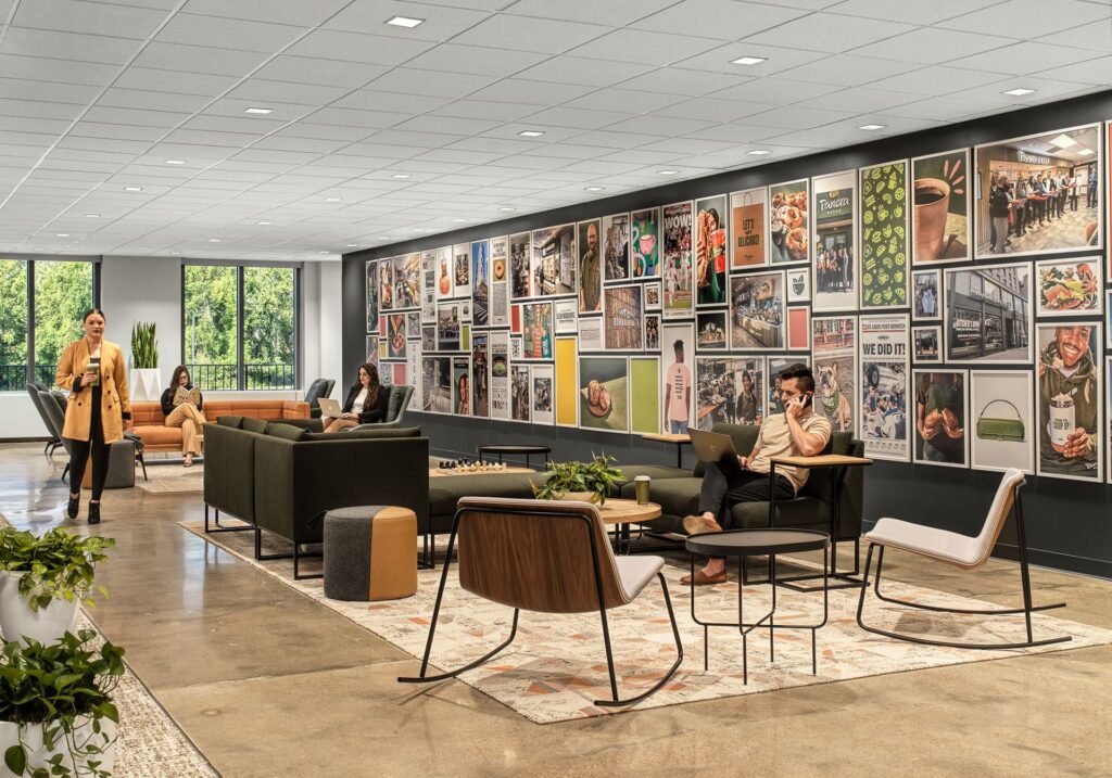 Open workplace lounge with blue seating, collaborative tables, and graphic wall art