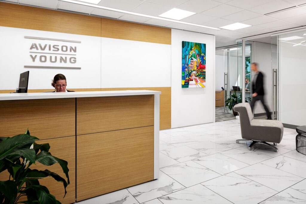 Contemporary Avison Young reception desk and lobby in St. Louis with warm wood finishes and artwork