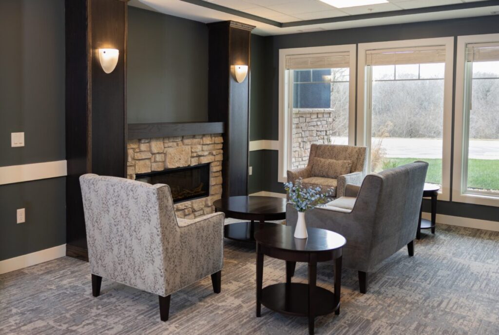 Contemporary lounge with a fireplace, upholstered seating, warm wood finishes, and large windows