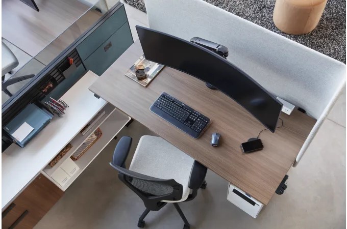 Modern office workstation with a curved monitor, wood desk, ergonomic chair, and built-in storage.