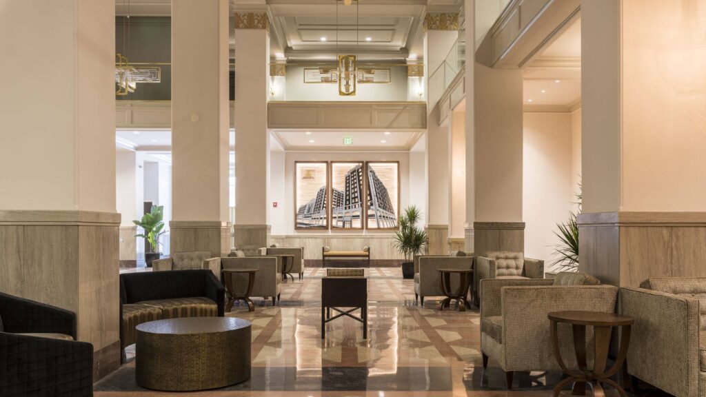 Elegant commercial lobby with marble columns, lounge seating, and a central fireplace