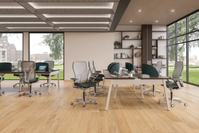 Bright open-plan office with collaborative workstations, ergonomic chairs, privacy screens, wood flooring, and floor-to-ceiling windows.