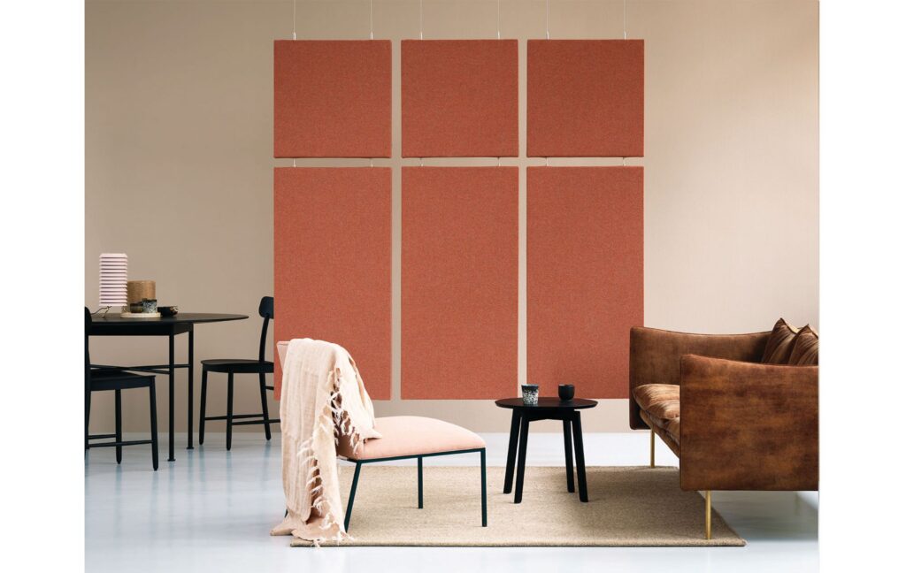 Modern office lounge with rust-colored acoustic wall panels, leather seating, café tables, and a small side table.
