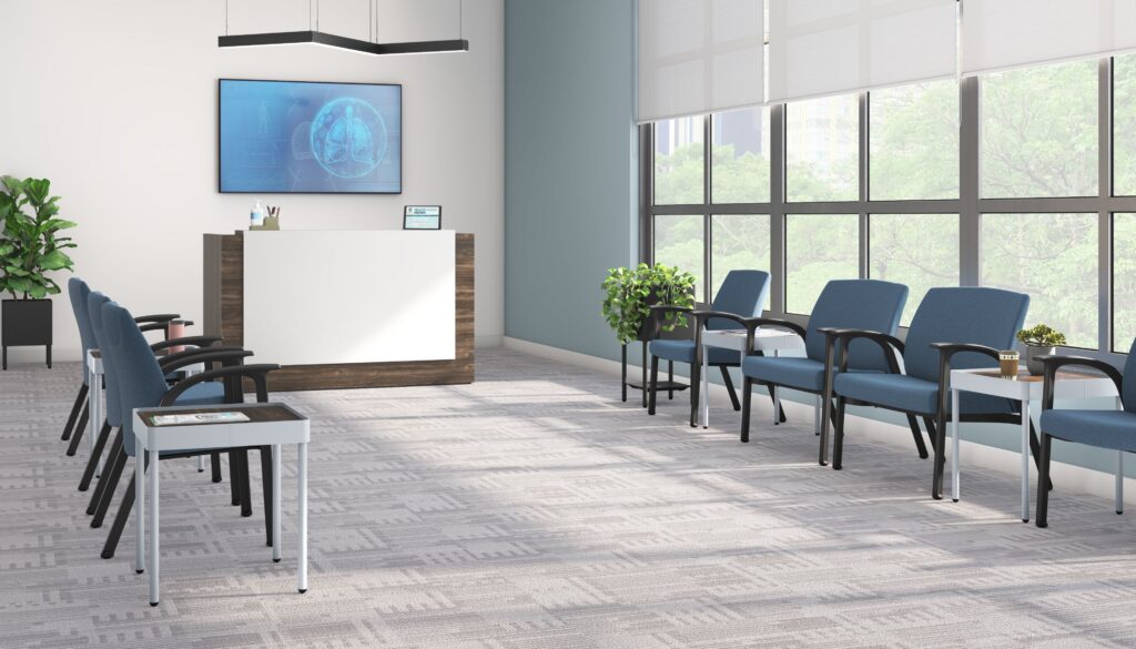 Modern healthcare waiting room with blue guest chairs, reception desk, side tables, indoor plants, and large windows.