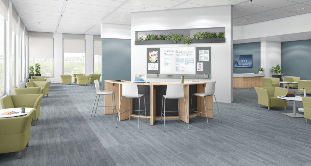 Flexible collaborative office with a central high-top table, bar stools, writable planning board, integrated greenery, and surrounding lounge seating.
