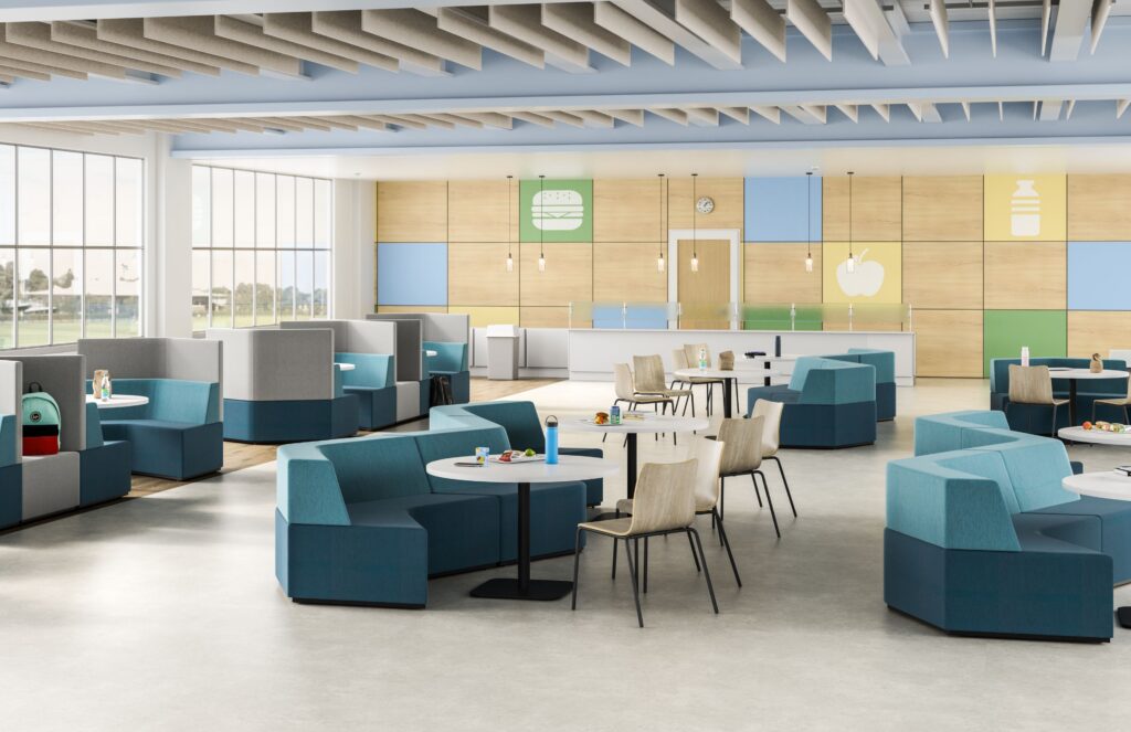 Large cafeteria-style collaboration space with teal modular booths, round tables, wood chairs, colorful wall panels, and suspended acoustic ceiling baffles.