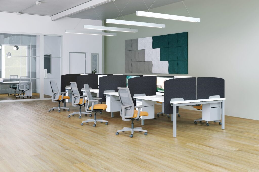 Open-plan office with clustered workstations, ergonomic chairs, privacy screens, suspended linear lighting, and geometric acoustic wall panels.